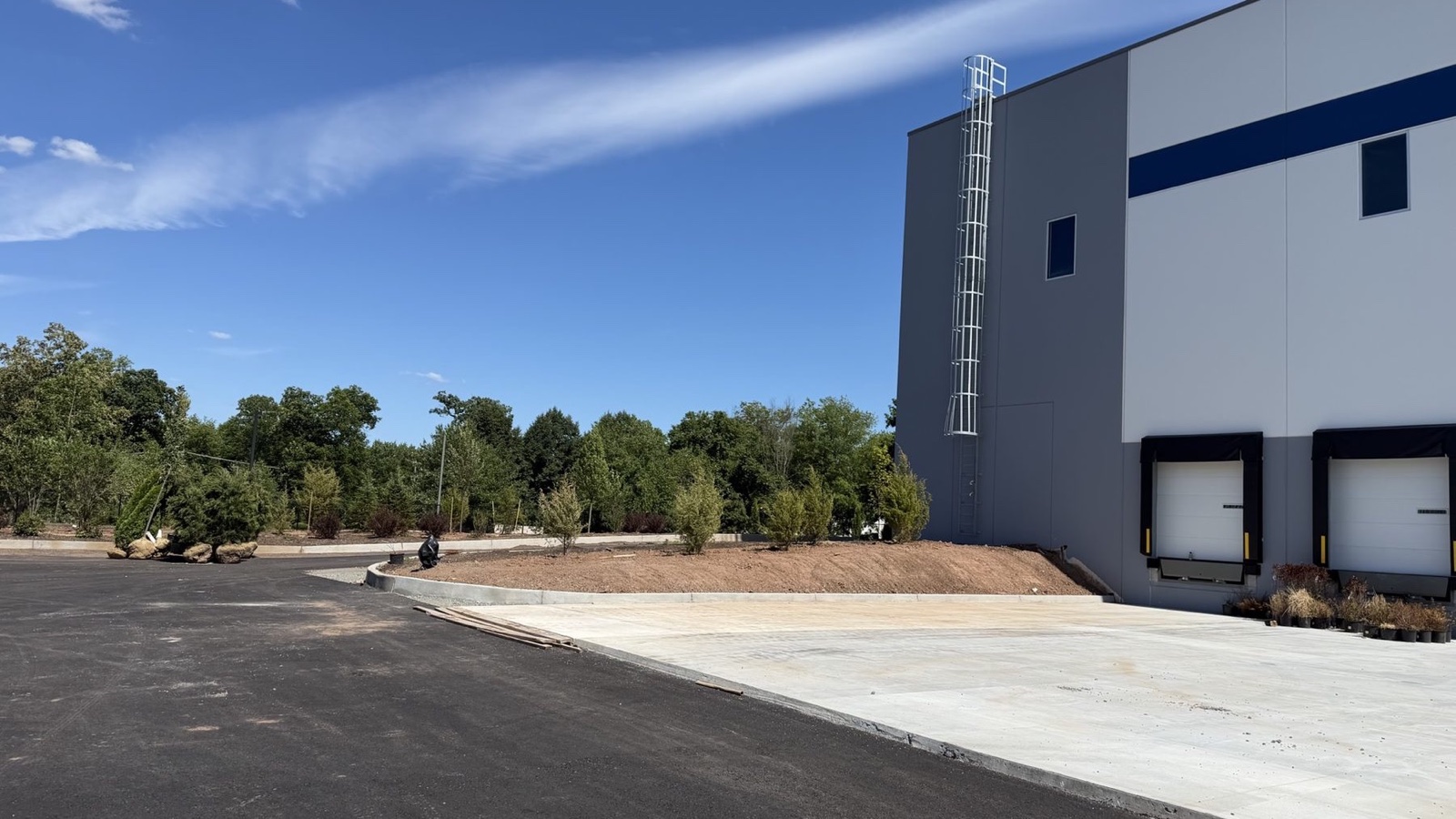Gray-and-white precast warehouse at 31 Schoolhouse Road during paving and landscape work in Franklin Township, New Jersey.